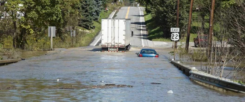 A semi truck driving out of a flooded road
