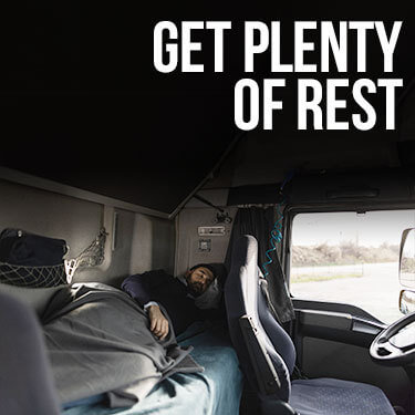A truck driver sleeping in the bed of their truck