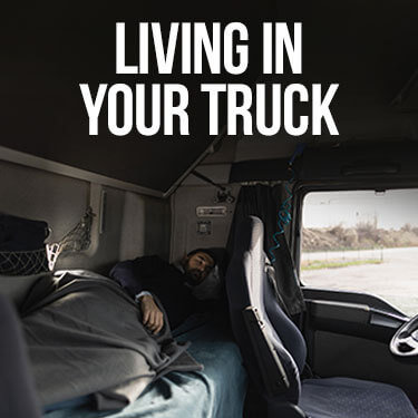 A truck driver sleeping in the back of their truck