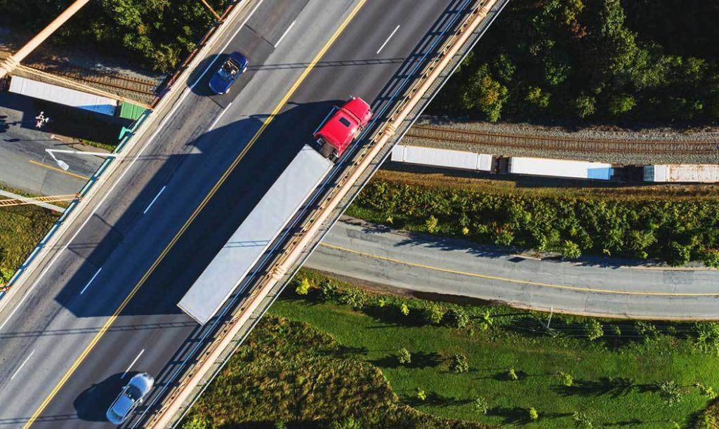 An overhead view of a semi truck on a four lane highway.