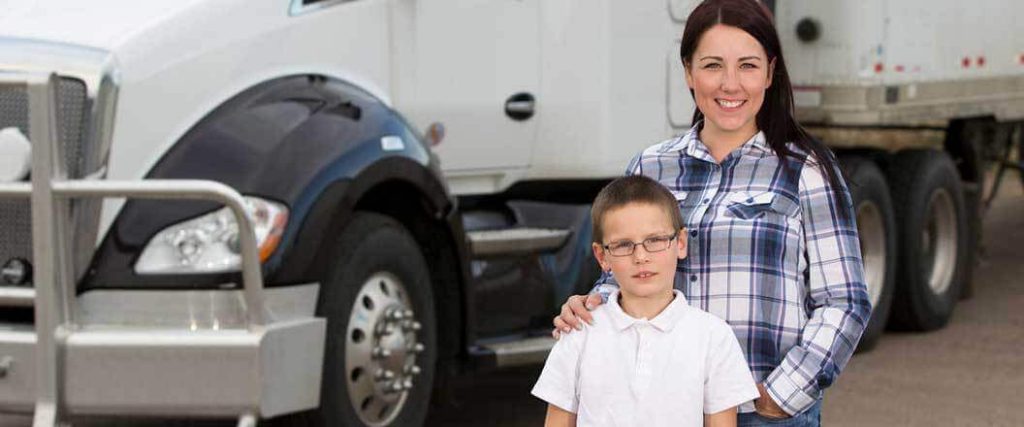A mother and son standing next to a semi truck.